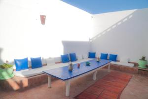 um sofá com almofadas azuis e uma mesa num quarto em Riad Dar Afram em Essaouira