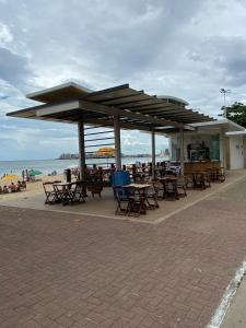 ein Picknickplatz mit Tischen und Stühlen am Strand in der Unterkunft Apartamento de frente para o mar in Guarapari