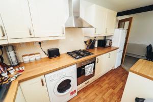 a kitchen with white cabinets and a washer and dryer at Cottages in Derbyshire - Orchard Cottage in Belper +10 photos