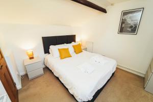 a bedroom with a large white bed with orange pillows at Cottages in Derbyshire - Orchard Cottage in Belper