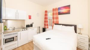 a white bedroom with a bed and a kitchen at Luxury Shirley Apartments close to Solent Uni and Southampton Central Train Station in Southampton