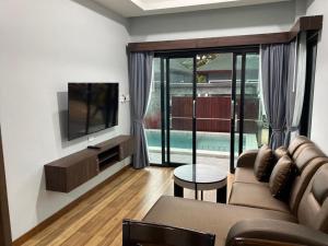 ein Wohnzimmer mit einem Sofa und einem TV in der Unterkunft KP Family Pool Villa Aonang Krabi in Ao Nang Beach