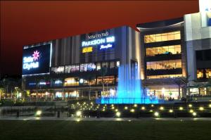a building with a fountain in front of it at night at Luma Casa Capsule Hotel, Sunsuria Forum Setia Alam in Shah Alam