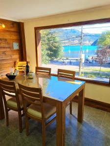 ein Esszimmer mit einem Tisch und Stühlen sowie einem großen Fenster in der Unterkunft Puerto Lacar Lodge SMARG in San Martín de los Andes