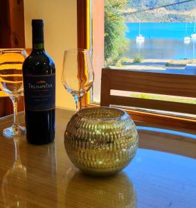 a bottle of wine and a wine glass on a table at Puerto Lacar Lodge SMARG in San Martín de los Andes