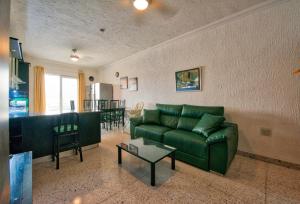 a living room with a green couch and a table at BEACHFRONT with Seaviews Apartment No56 Award Winner Unbeatable Location for Closeness to the Sea Ideal for Guests looking for Winter Spring and Autumn Breaks in Sunny Malta Also Ideal for Coastal Hikers in Mellieħa