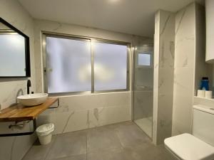a bathroom with a shower and a sink and a window at Shanti Rooms in Valencia