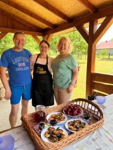tres personas de pie frente a una mesa con una bandeja de comida en Садиба під Чертежиком 2, en Kolochava