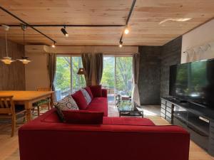 salon z czerwoną kanapą i telewizorem z płaskim ekranem w obiekcie スイートヴィラ 四季terrace箱根仙石原 w mieście Sengokuhara
