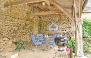 eine Terrasse mit einem Tisch, Stühlen und einem Grill in der Unterkunft Lovely Home In Valojoulx in Valojoulx + 9 Fotos