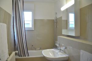 a bathroom with a sink and a tub and a shower at Rent a Home Landskronstrasse - Self Check-In in Basel +4 photos