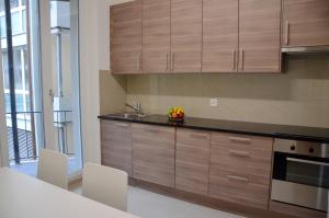 a kitchen with wooden cabinets and a sink at Rent a Home Landskronstrasse - Self Check-In in Basel