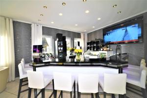 a bar in a room with white chairs and a tv at Ascot Hotel in Remscheid