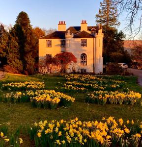 a house with a field of flowers in front of it at Creran Apartment, Kinlochlaich House in Appin