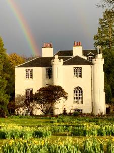 a rainbow over a large white house with at Creran Apartment, Kinlochlaich House in Appin