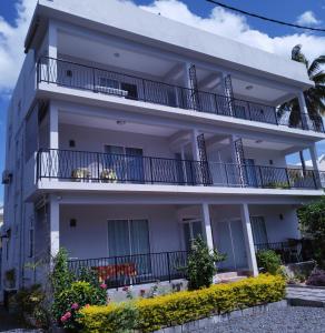 un edificio de apartamentos blanco con balcones y flores en Villa Alexis - Location de vacances à Trou aux Biches, en Trou aux Biches