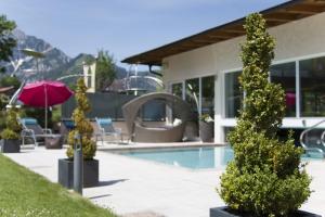 a swimming pool with trees in front of a building at Liebes Caroline 4-Sterne-Hotel in Pertisau