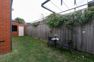 a backyard with two chairs and a table and a fence at Heart of McKinnon Unit by Ready Set Host in Melbourne
