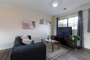 a living room with a blue couch and a flat screen tv at Heart of McKinnon Unit by Ready Set Host in Melbourne