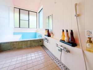 La salle de bains est pourvue d'une baignoire et d'un lavabo avec des bouteilles. dans l'établissement Suite Villa Jogasaki CHABA, à Itō