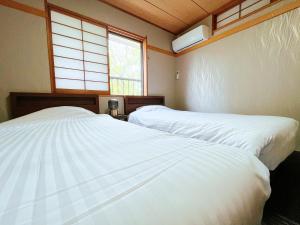 - 2 lits blancs dans une chambre avec fenêtre dans l'établissement Suite Villa Jogasaki CHABA, à Itō
