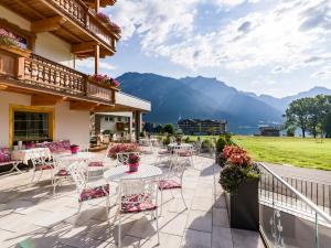a patio with tables and chairs with mountains in the background at Liebes Caroline 4-Sterne-Hotel in Pertisau