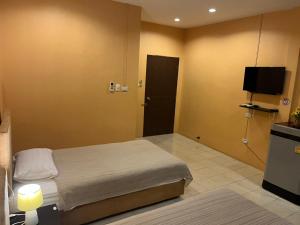 ein Hotelzimmer mit einem Bett und einem TV in der Unterkunft Khaolak inn in Khao Lak