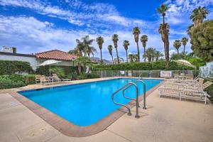 a large swimming pool with chairs and palm trees at Rancho Mirage Condo on Fairway with Resort Amenities! in Rancho Mirage