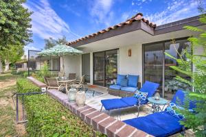 a patio with blue chairs and an umbrella at Rancho Mirage Condo on Fairway with Resort Amenities! in Rancho Mirage