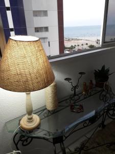 a lamp on a glass table with a view of the beach at apartamento na praia de Iracema com vista mar in Fortaleza