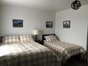twee bedden in een kamer met witte muren bij Mon Coin de Pays in Sacré-Coeur-Saguenay
