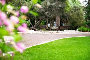 Deux bancs dans un parc avec de l'herbe et des fleurs dans l'établissement Eden Inn, à Zikhron Yaakov