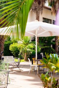 patio ze stołami, krzesłami i parasolem w obiekcie Eden Inn w mieście Zichron Ja’akow