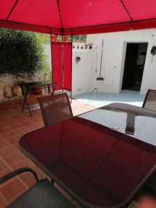 einen Tisch und Stühle unter einem roten Regenschirm auf einer Terrasse in der Unterkunft CASA PACO - Maison Andalousie in Cútar