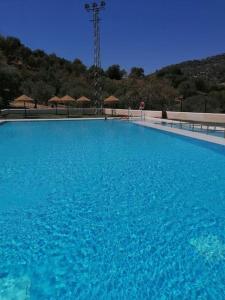 una gran piscina de agua azul con sombrillas de fondo en CASA PACO - Maison Andalousie en Cútar
