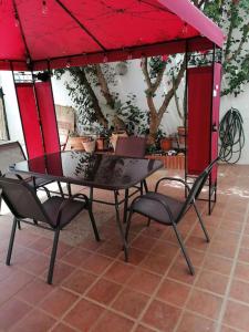een tafel en stoelen onder een rode paraplu bij CASA PACO - Maison Andalousie in Cútar