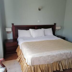 uma cama grande num quarto com duas mesas de cabeceira em The Congress Hotel em Accra