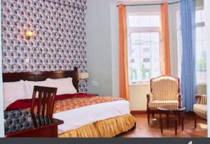 1 dormitorio con 1 cama, 2 sillas y ventana en The Congress Hotel, en Accra