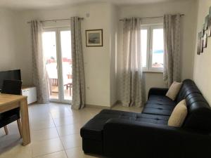 un salon avec un canapé noir et une table dans l'établissement Apartments Baldo, à Orebić