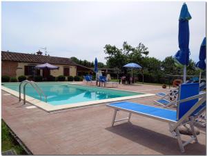 a large swimming pool with blue chairs and umbrellas at Villino Cortona - Casa vacanze a Cortona con piscina privata WiFi, AC - Toscana - Nelle vicinanze Perugia, Assisi, Montepulciano, Pienza, Siena in Cortona