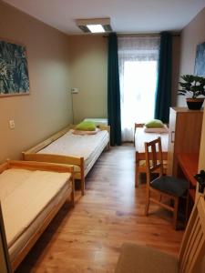 Habitación con 2 camas, mesa y silla en Hostel Gliwice Centrum, en Gliwice