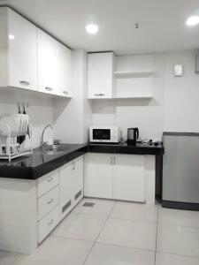 a kitchen with white cabinets and a black counter top at Tapeer Homestay 13CC99 @D Perdana Kota Bharu in Kota Bharu