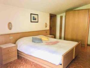 a bedroom with a large white bed with a wooden frame at Appartamento Fodom in Arabba