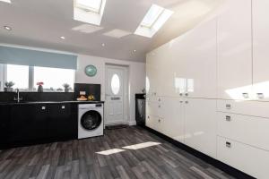 a kitchen with white cabinets and a washing machine at Auckland View - a comfy & spacious 4bed with views in Coundon