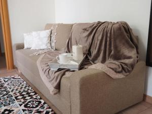 um sofá com um cobertor e duas chávenas. em “Come A Casa” Ferrara em Ferrara