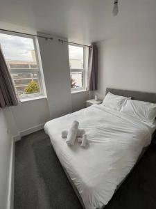a white bed with two teddy bears on it at 2 Bed Apt, 20 mins from London, central romford in London
