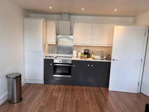 a kitchen with white cabinets and a black oven at 2 Bed Apt, 20 mins from London, central romford in London