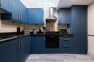 a blue kitchen with black counters and appliances at Free Parking - Shrewsbury Square - Central 2 Bedroom Top Floor Apartment in Shrewsbury