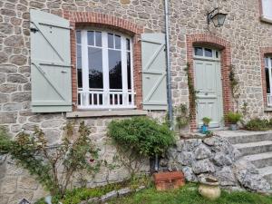 Casa de piedra con puertas verdes y pared de piedra en Bon Chez Nous en Saint-Amand-Jartoudeix