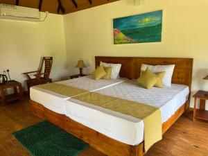 una camera da letto con un grande letto in legno con cuscini gialli di Saffron Lake Yala a Tissamaharama